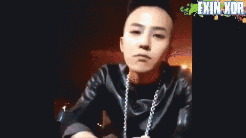 a young man with a shaved head is wearing a black leather jacket and a necklace .