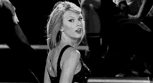 a black and white photo of taylor swift dancing on stage .