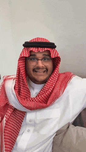 a man wearing glasses and a red and white scarf smiles