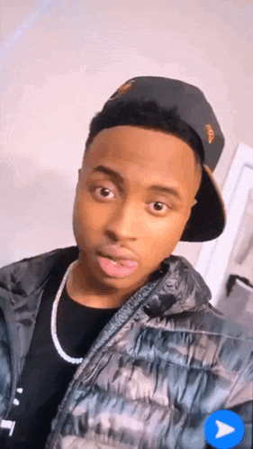 a young man wearing a hat and a jacket looks at the camera .