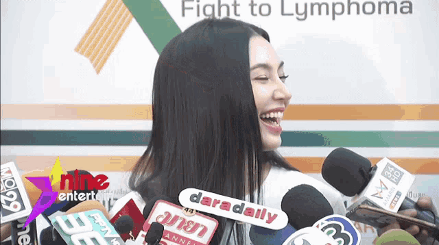 a woman is smiling in front of a sign that says fight to lymphoma on it