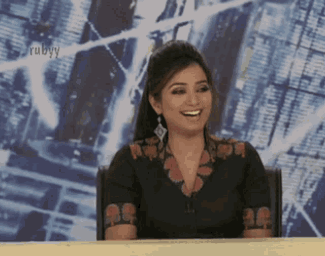 a woman is smiling in front of a wall that says rubyy on it