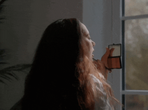 a woman is applying makeup to her face in front of a mirror .