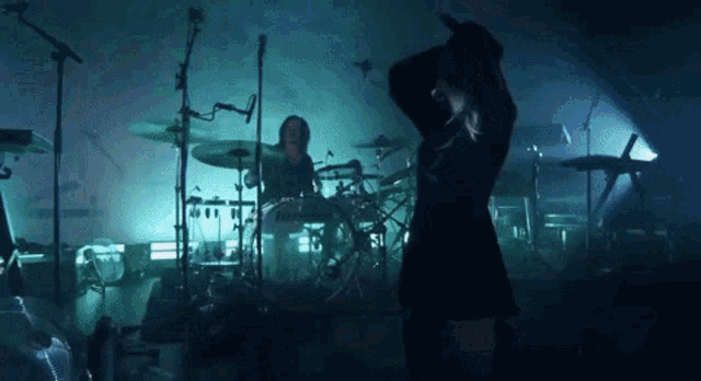 a woman is dancing on stage in front of a drum set .