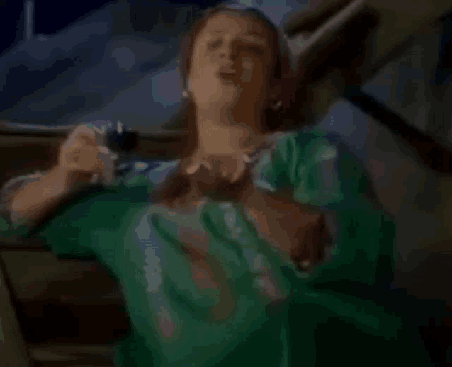 a woman in a green dress is holding a glass of wine in her hand .