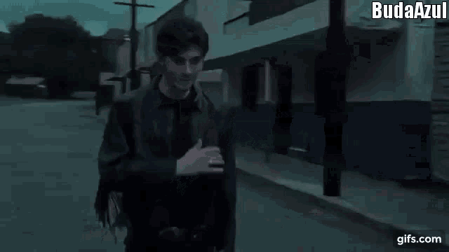 a man in a black leather jacket is walking down a street .
