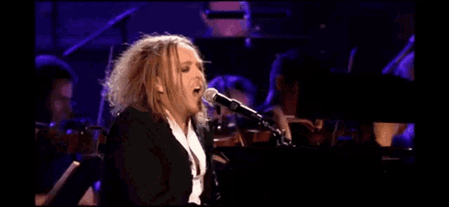 a man singing into a microphone while playing piano