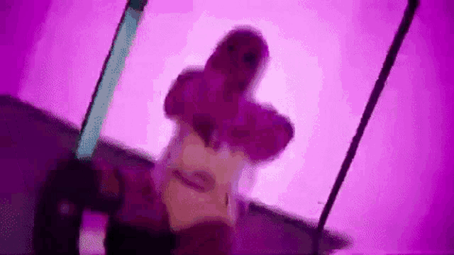 a woman is standing in front of a purple background holding a sword .