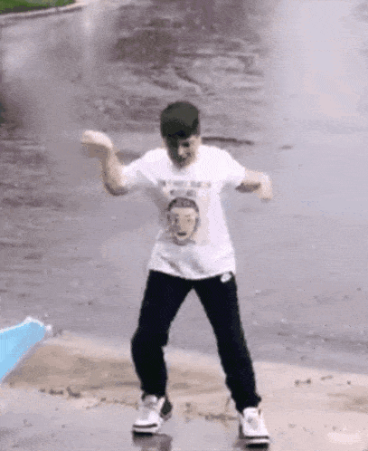 a man is dancing in the rain wearing a white shirt with a picture of a man 's face on it .