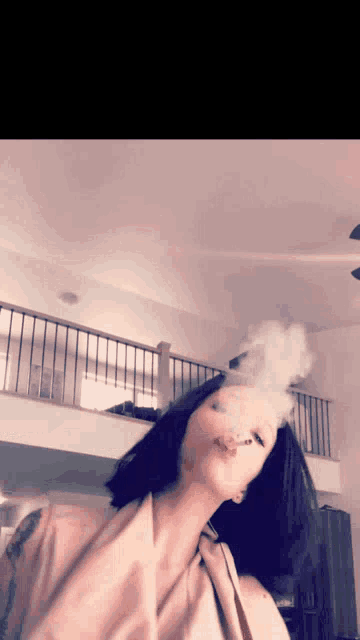 a woman is smoking a cigarette in a room with a balcony