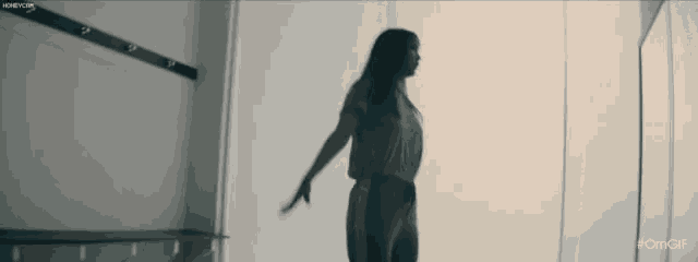 a woman is standing in front of a mirror with her arms outstretched in a room .