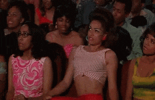 a woman in a crop top is sitting in a crowd of people .