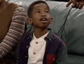 a young boy is sitting on a couch with a woman and looking up .