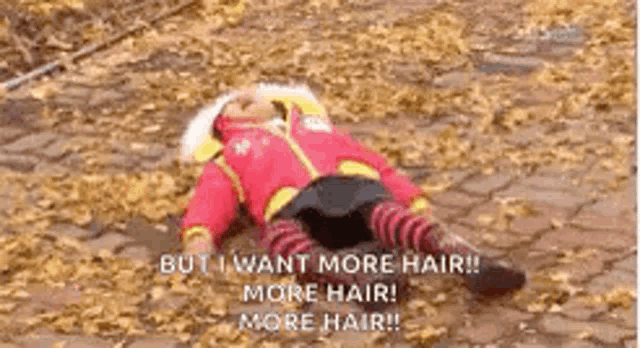 a child is laying on the ground covered in leaves and says `` but i want more hair ! ''