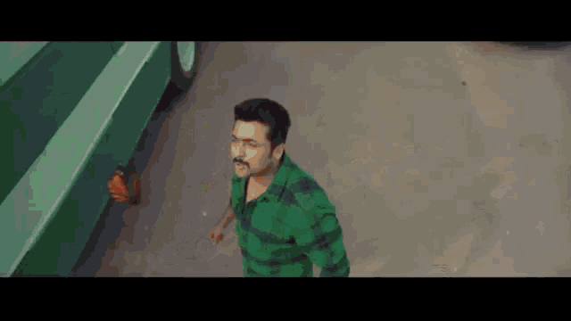 a man in a green shirt with a mustache is walking down the street .