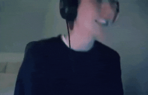 a man wearing headphones and a headset is smiling and looking at the camera .