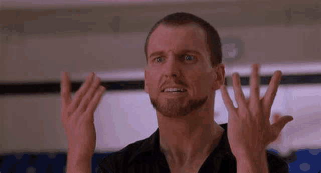 a man with a beard is making a face with his hands in the air .