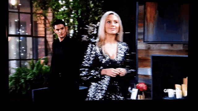 a woman in a sequined dress stands in front of a man