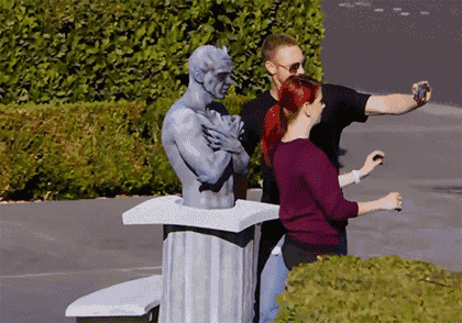 a man is taking a selfie with a statue of a man