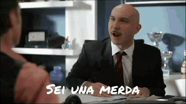 a man in a suit and tie is talking to another man and the words sei una merda are visible