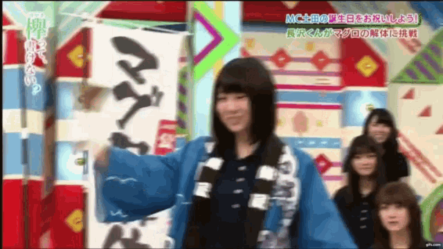 a girl in a blue kimono is holding a sign that says ' a ' on it