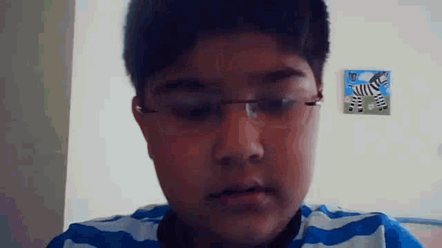 a young boy wearing glasses is looking at the camera .