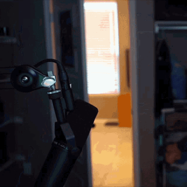a green microphone is sitting in a dark room with a window in the background