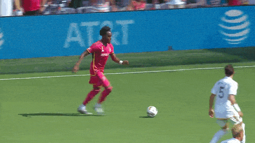 two soccer players on a field with an at & t banner behind them