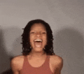 a woman in a tank top is laughing with her mouth wide open .