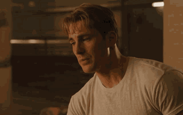 a man in a white t-shirt looks to his left