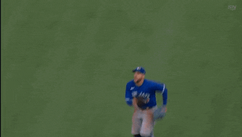 a baseball player wearing a blue jays jersey is running on the field .