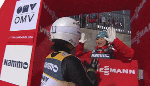 a man wearing a helmet is giving a high five to another man