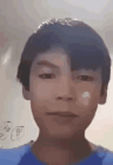 a young boy wearing a blue shirt is making a funny face .