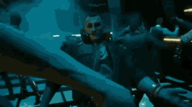 a man with a cigarette in his mouth is standing in a dark room .