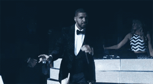 a man in a tuxedo is holding a microphone in front of a crowd