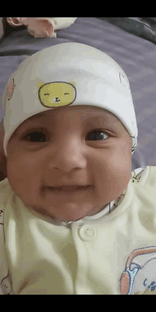 a baby is wearing a white hat with a yellow smiley face on it