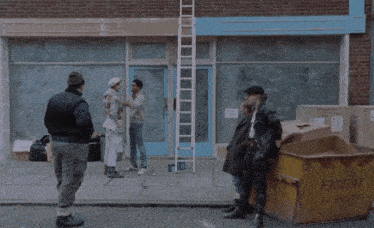 a man with a blue sticker on his face is hugging another man in front of a building