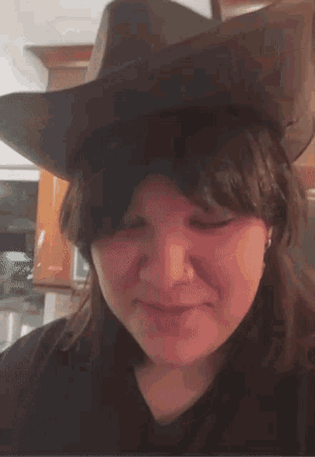 a woman wearing a cowboy hat looks at the camera with her eyes closed