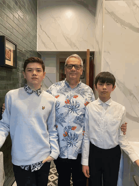 a man wearing a shirt that says ' lyle & scott ' on it stands next to two boys