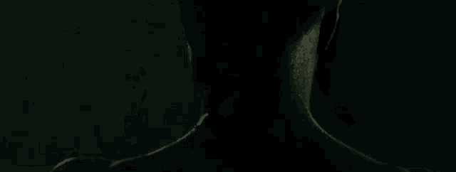 a man in a black suit is standing in the dark .