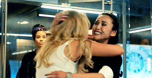 two women are hugging each other in a room and one of them is crying .