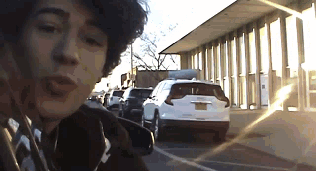 a man is taking a picture of himself in front of a building and a white car