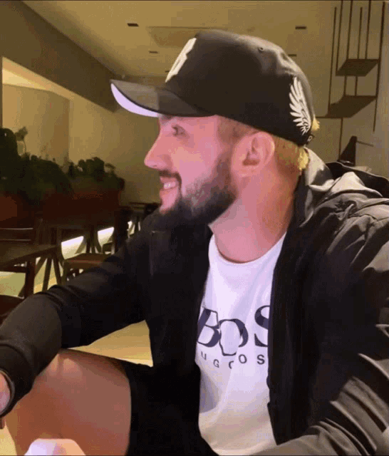 a man wearing a black hat and a white boss hugo boss shirt