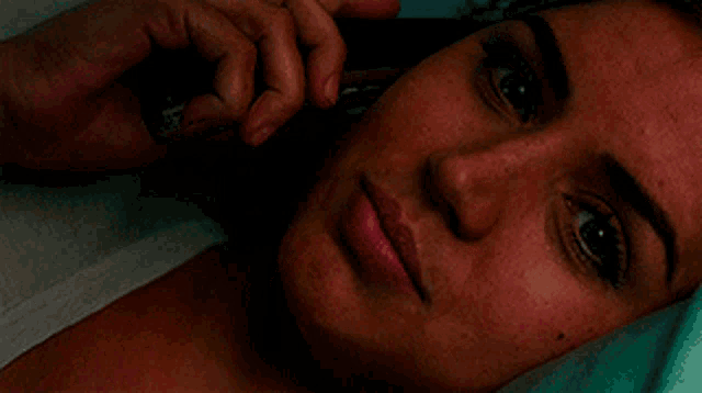 a close up of a woman laying down talking on a cell phone
