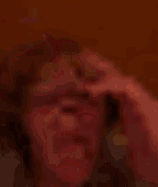 a blurry picture of a person 's face with a finger pointing to it .