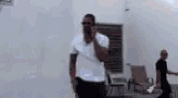 a man in a white shirt is talking on a cell phone .