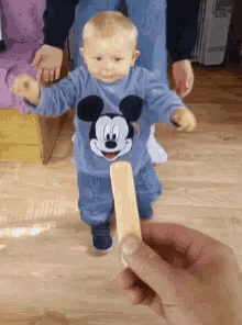 a baby wearing a mickey mouse shirt is being held by a person