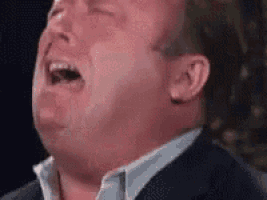 a man in a suit is crying with his mouth open and his eyes closed .