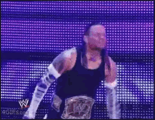 a man in a black tank top and white gloves is standing in front of a screen that says ' 4gifs '