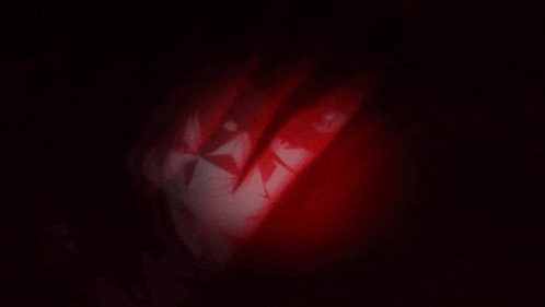 a close up of a person 's face with a red light coming out of it in the dark .